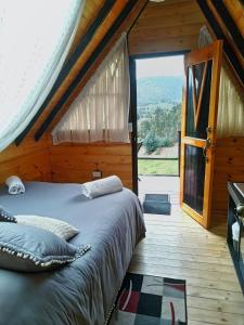 Cama en habitación con ventana grande en Glamping refugio Gaia, en Paipa