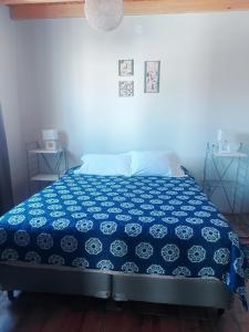 Cama en habitación con manta azul y blanca en Don Trujo 2 - parque y pileta en Mendoza