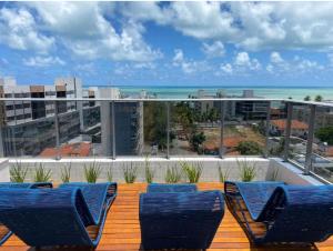 2 sillas azules en una terraza con vistas al océano en Box 150 Joia Rara no Caribessa, en João Pessoa