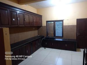 an empty kitchen with wooden cabinets and a window at Villa Borobudur Malino 