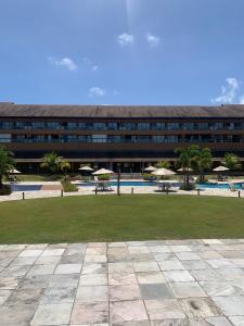 a large building with a pool and tables and umbrellas at FLAT 210 - ECORESORT PRAIA DOS CARNEIROS in Tamandaré