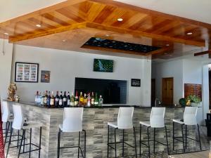 達沃市的住宿－GEM Crystal Water Resort，酒吧设有白色凳子和瓶装葡萄酒