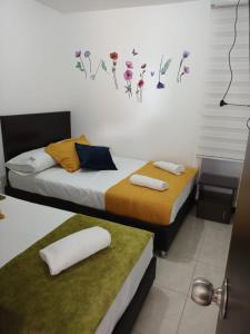 1 dormitorio con 2 camas y toallas. en Colibrí Cafeterito, en Montenegro