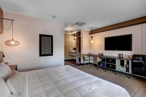 a hotel room with a bed and a flat screen tv at Mahala - 21 and Over in Palm Springs