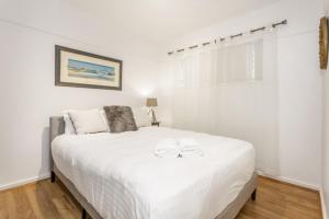 um quarto com uma cama branca com duas toalhas em Zoo View Apartment - EXECUTIVE ESCAPES em Perth