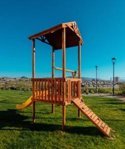 un parque infantil de madera con un tobogán en el césped en Tranquilidad Veraniega Pet Friendly, en La Serena