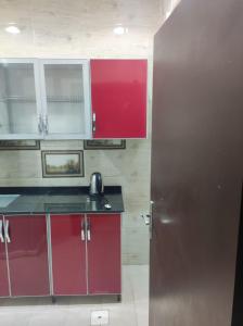 a kitchen with red cabinets and a silver refrigerator at الياسمين للشقق المفروشة in Jeddah