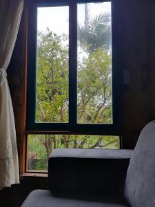 ventana en una habitación con cama y árboles en Jabuticasa Cabana de madeira na praia, en Penha