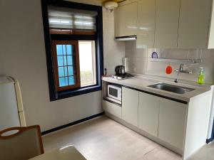 una pequeña cocina con fregadero y ventana en 롬하우스 Rom House en Seogwipo