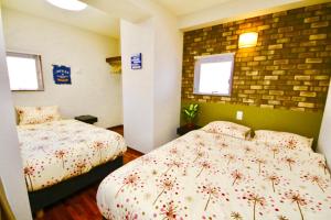 a bedroom with two beds and a brick wall at Chura Gahna House Tsubogawa Naha in Naha