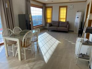 sala de estar con mesa, sillas y sofá en 롬하우스 Rom House en Seogwipo