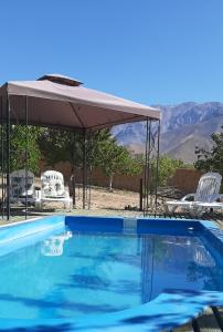 a swimming pool with a canopy and two chairs and a table at Cabaña entre Nogales in Horcon