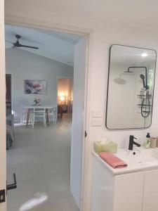 ein weißes Badezimmer mit einem Waschbecken und einem Spiegel in der Unterkunft Adorable 2 bedroom unit, set in lush gardens in McMinns Lagoon