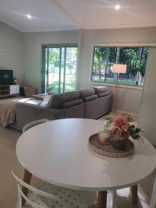 Adorable 2 bedroom unit, set in lush gardens في McMinns Lagoon: غرفة معيشة مع طاولة بيضاء وأريكة