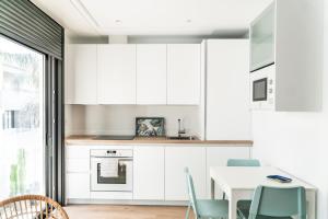 une cuisine avec des armoires blanches et une table et des chaises dans l'établissement Las Canteras Lighthouse, à Las Palmas de Gran Canaria