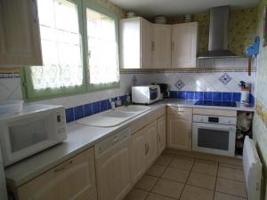 a kitchen with white appliances and blue tiles at Évasion rustique avec cheminée et vélos, proche du Mans - FR-1-410-166 in Congé-sur-Orne +3 photos