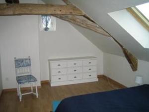 una camera con letto, sedia e cassettiera di Gîte spacieux rénové en 1850 avec grand jardin, terrasse, jeux pour enfants et équipements modernes ! - FR-1-410-172 a Pontvallain