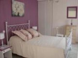 ein Schlafzimmer mit einem weißen Bett mit lila Wänden in der Unterkunft Gîte Vallon-sur-Gée, 2 pièces, 2 personnes - FR-1-410-187 in Vallon-sur-Gée