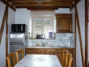 een keuken met een tafel en een koelkast bij Gîte Épineu-le-Chevreuil, 3 pièces, 4 personnes - FR-1-410-198 in Épineu-le-Chevreuil