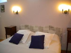 ein weißes Bett mit zwei blauen Kissen darauf in der Unterkunft Gîte Vennecy, 4 pièces, 6 personnes - FR-1-590-181 in Vennecy