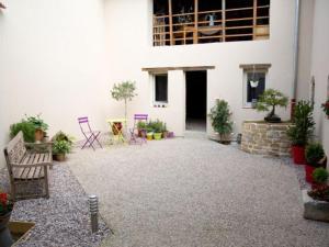 a courtyard of a white building with chairs and plants at Gîte familial près de Nancy avec grand jardin, spa, salle de jeux, et équipements pêche - FR-1-584-15 in Laneuveville-devant-Bayon