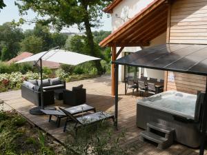 une terrasse avec un bain à remous à côté d'une maison dans l'établissement Maison de campagne éco-construite, spa, proche Nancy, tout confort, petit-déjeuner inclus - FR-1-584-83, à Voinémont