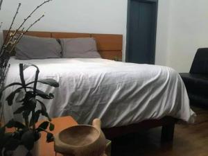 Una cama con una manta blanca y una mesa con una planta en Departamento en Colonia Roma con 2 habitaciones, en Ciudad de México