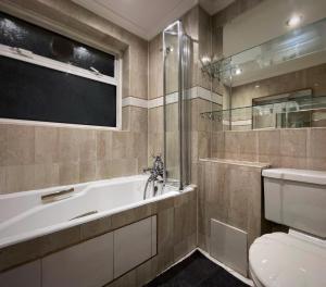 a bathroom with a tub and a toilet and a window at Vintage 3 Bedroom House near Catford in London