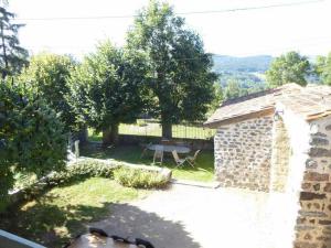 Un patio trasero con un edificio de piedra y una mesa de picnic. en Élégante maison de maître XVIIIe, jardin clos 500m², nature, proche Puy-en-Velay, 11 pers., cosy & confort - FR-1-582-315, en Arsac-en-Velay