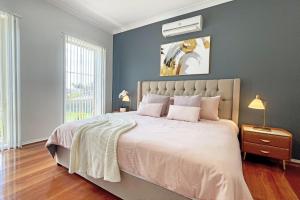 1 dormitorio con 1 cama grande y pared gris en Spacious 5BR House in Hallam near Bunjil Place, en Hallam