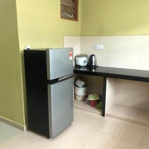 eine Küche mit einer schwarzen Theke und einem Kühlschrank in der Unterkunft ANGAH HOMESTAY LANGKAWI in Kuah