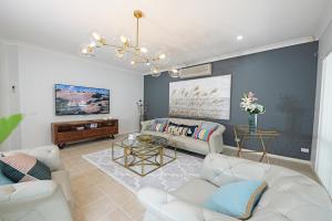 sala de estar con muebles blancos y pared azul en Spacious 5BR House in Hallam near Bunjil Place, en Hallam