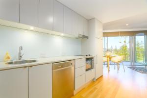 a white kitchen with a sink and a table at Resort Rooms at Bells Boulevard in Kingscliff