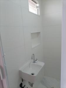 a white bathroom with a sink and a window at Pousada Cama & Café in Navegantes