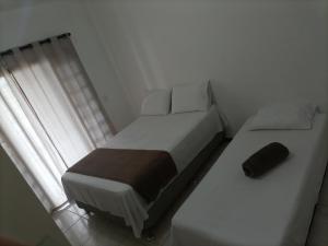 a bedroom with two beds and a window at Pousada Cama & Café in Navegantes