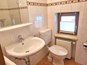 uma casa de banho branca com um lavatório e um WC em Ferienwohnungen Hamberger em Sachrang