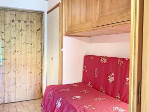 a bedroom with a red bed and a wooden cabinet at Studio cosy pour 3 avec terrasse, parking et casier à ski à Combloux - FR-1-560-77 in Combloux