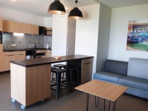 a kitchen and living room with a bar and a couch at Appartement PMR avec balcon, piscine, parking et plage à La Tranche-sur-Mer - FR-1-194-229 in La Tranche-sur-Mer