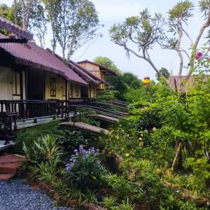 a garden in front of a building with flowers at Brown House Resort in Can Tho