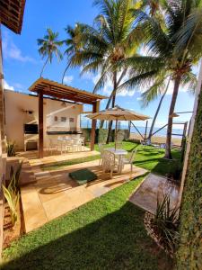 a patio with a table and an umbrella at Casa à beira mar de Maragogi com 3 quartos, 4 banheiros e Área Verde in Maragogi