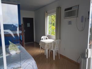 um quarto com uma cama, uma mesa e cadeiras em Suítes Encanto do Pai em Praia de Araçatiba