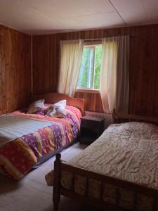 a bedroom with two beds and a window at Hostal Flor del Meli in Dalcahue