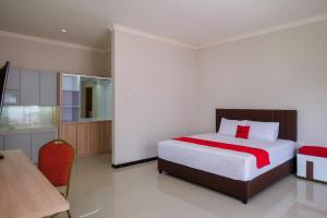 RedDoorz Syariah near Solo Paragon Mall 2 في Bonorejo: غرفة نوم بسرير وطاولة ومكتب