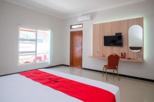 RedDoorz Syariah near Solo Paragon Mall 2 في Bonorejo: غرفة نوم بسرير كبير مع بطانية حمراء