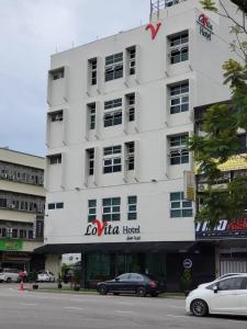a white building with a car parked in front of it at Lovita Hotel Kuantan in Kuantan
