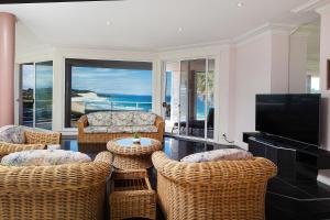 a living room with wicker chairs and a flat screen tv at The Pink Palace in Forster