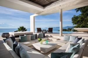 een woonkamer buiten met witte meubels en uitzicht op de oceaan bij Villa Celadon in Mae Nam