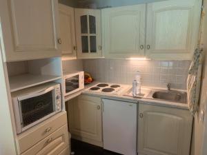 - une cuisine avec des placards blancs et un évier dans l'établissement Appartement Mont-Dore, 2 pièces, 6 personnes - FR-1-415-115, à Le Mont-Dore