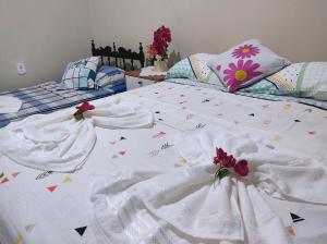 uma cama com lençóis brancos com bandeiras em Chalé Sol de Verão Macapá-Pi em Luis Correia
