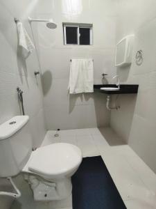 a white bathroom with a toilet and a sink at Chalé Sol de Verão Macapá-Pi in Luis Correia